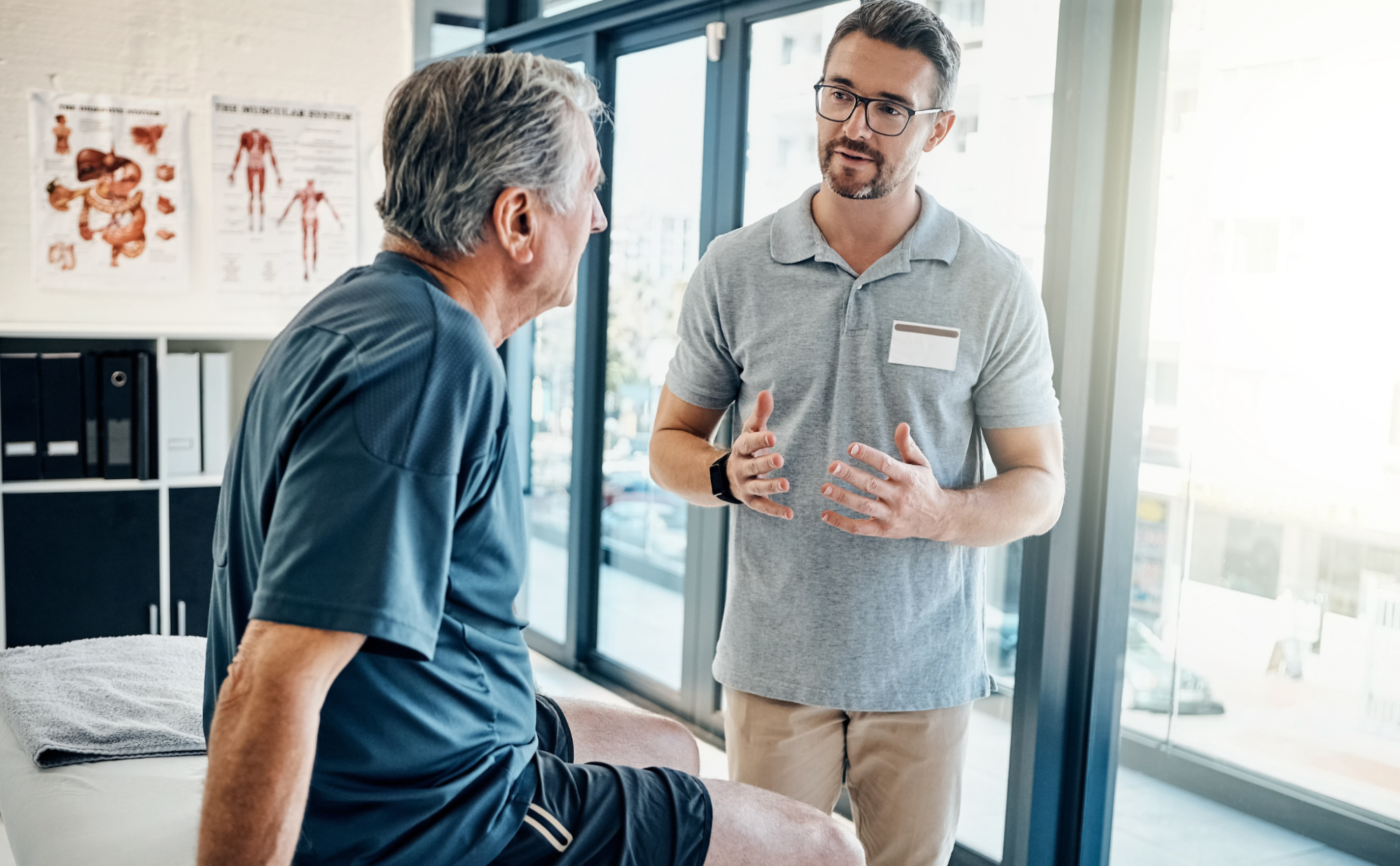 image1 A male medical practitioner explaining a personalized wellness treatment plan to a senior patient sitting on an examination table in a bright Safety Harbor clinical office.